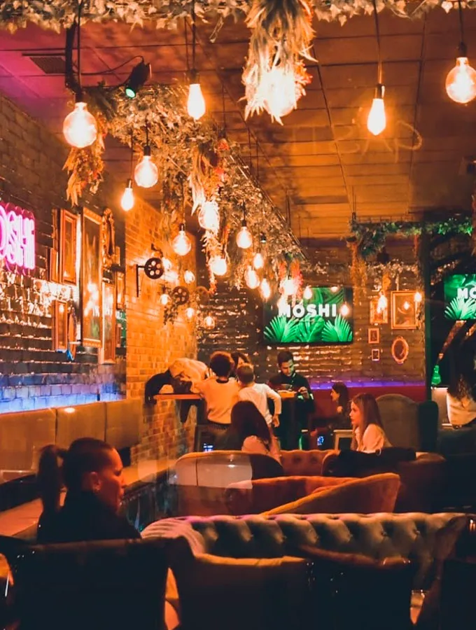Interior de Moshi con plantas, lámparas cálidas y sofás Chester